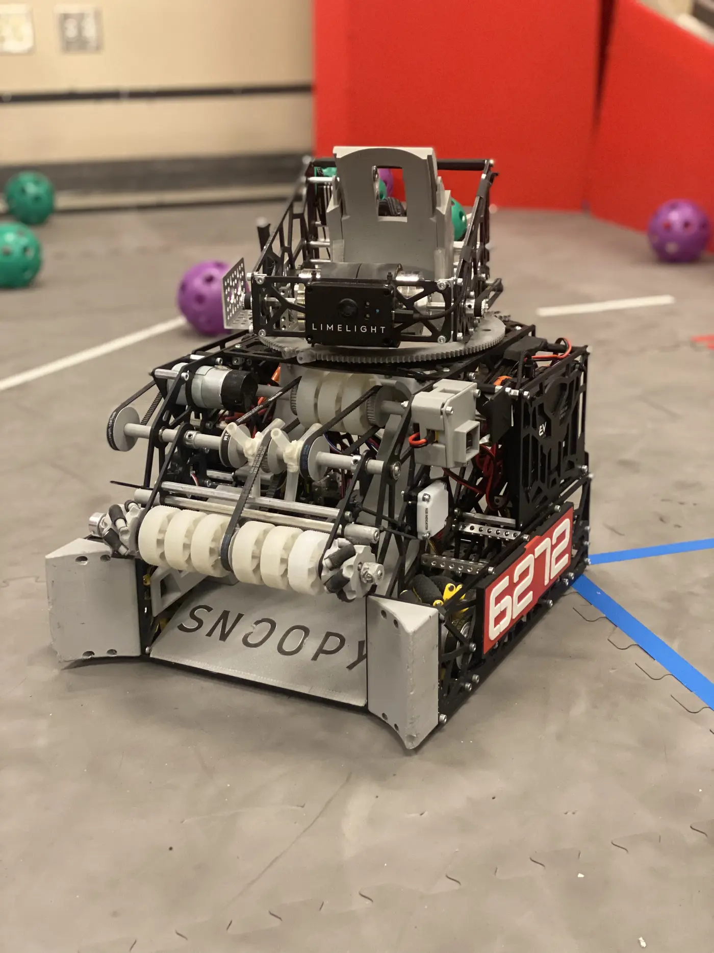The robot at competition, seen from the front: white 3D-printed intake rollers with belts at the bottom, a black and gray frame, and a Limelight camera on a rotating section on top.